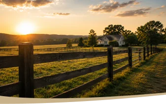 Sunset over a rural landscape with wooden fence, green fields, and a white farmhouse.