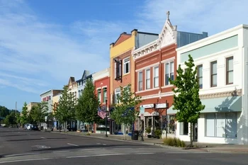 Street view of colorful historic downtown buildings with trees and clear blue sky.